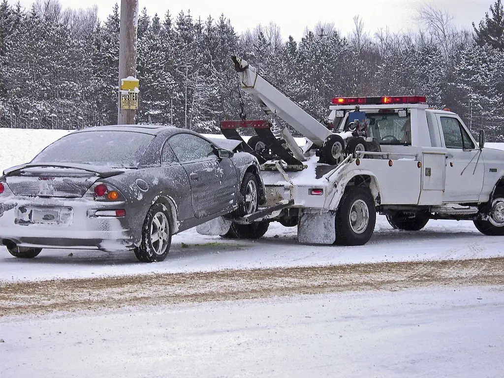 Dépannage rabat Dépanneuse transportant une voiture accidentée en hiver.